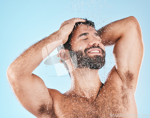 Image of Shower, grooming and a man cleaning his hair with shampoo in studio on a blue background for beauty. Hygiene, washing and bathroom with a handsome male wet with liquid while bathing for haircare