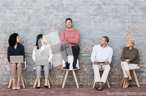 Image of Creative business people, waiting room and man standing out against a brick wall for interview, meeting or opportunity. Group of employee interns with technology looking at candidate for startup