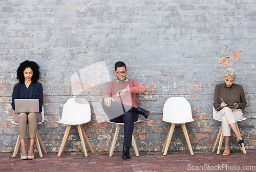 Image of Business people, waiting room and sitting on chairs against brick wall for interview, meeting or opportunity. Group of creative interns in social distancing, working and checking time for startup