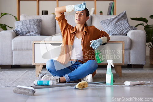 Image of Tired woman, cleaning and sitting on living room floor with detergent, chemicals or sanitizer spray for hygiene at home. Female domestic worker exhausted from housekeeping, chores or clean house