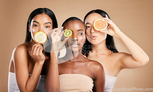 Image of Skincare, diversity and women with fruit, cosmetics and dermatology with friends on brown studio background. Face, vitamin c or ladies with natural beauty, girls and nutrition with healthy lifestyle