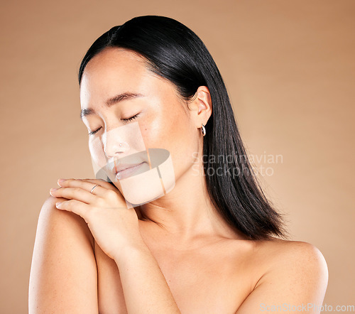 Image of Asian woman, eyes closed and isolated for skincare, beauty or cosmetics against a brown studio background. Japanese female, person or lady model with smile in satisfaction for perfect gentle skin