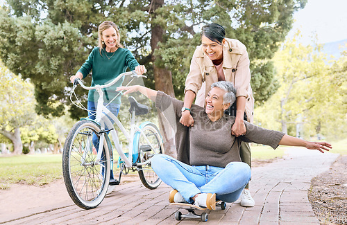 Image of Comic, happy and retirement friends in park for silly outdoor fun with skateboard and bicycle. Funny, goofy and senior women in nature with excited smile for bonding wellness together.