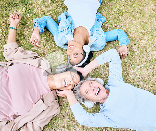 Image of Top view, senior or people and music headphones in silent disco, retirement friends fun or bonding community wellness. Smile, happy or elderly women lying on nature park grass and listening to radio