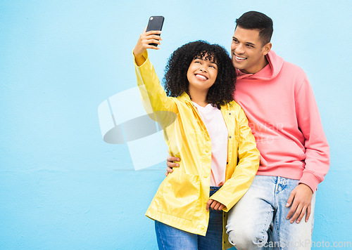 Image of Friends, phone and smile for selfie on a blue background for fashion, style or friendship together. Young man and woman smiling and looking at smartphone for photo leaning on a wall mockup