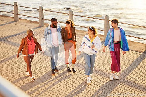 Image of Diversity, friends and walking seaside, talking and break in summer holiday, bonding and conversation. Multiracial, men and women on promenade, discussion and vacation with sunshine or relax together