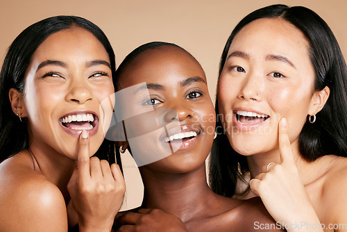 Image of Skincare, beauty and multicultural women smile and point at skin on studio background. Health, wellness and luxury cosmetics, healthy care and happy, beautiful and friendly people with natural makeup