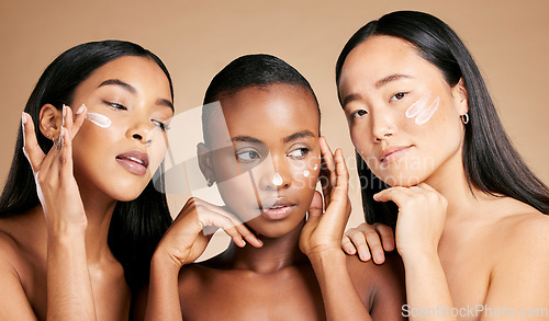 Image of Face cream, skincare and women in studio for wellness, grooming and hygiene against brown background. Friends, beauty and lotion for girl group with different, facial and skin product while isolated