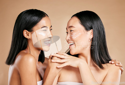 Image of Laughing, beauty and excited women with cream for face isolated on beige studio background. Wellness, smile and Asian model friends with sunscreen for love of cosmetics and dermatology on a backdrop