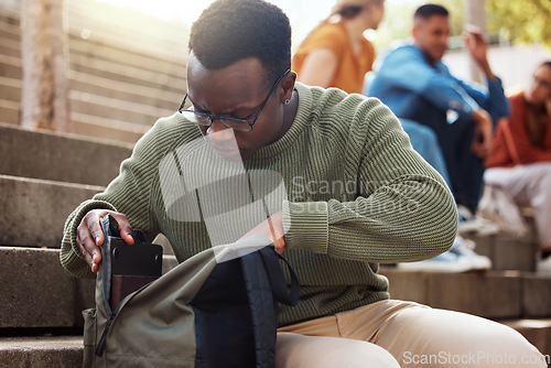 Image of University, student and black man looking in bag at campus for learning, studying or lost knowledge book. College steps, scholarship and male checking or searching backpack for missing item outdoors.