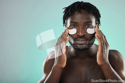 Image of Skincare, eye pads and portrait of a black man in studio for healthy, cosmetic and natural face routine. Health, wellness and African guy with a facial treatment by blue background with mockup space.