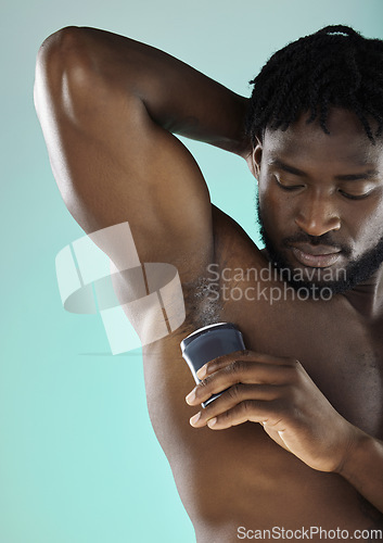 Image of Grooming, hygiene and black man with armpit deodorant isolated on a blue background in studio. Skincare, cleaning and African model with a product for body odor and morning routine on a backdrop