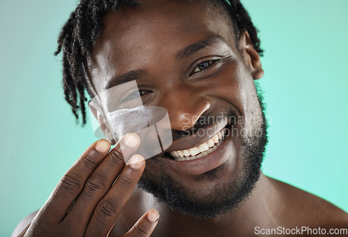 Image of Skincare, face cream and portrait of a black man in a studio with a beauty, health and natural skin routine. Wellness, cosmetic and African guy with facial spf, lotion or creme by a blue background.