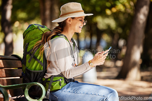 Image of Woman, backpack or phone in travel, sightseeing or adventure in nature park, trees forest or Canada woods. Smile, happy or tourist on mobile technology for gps map, location or hiking path research