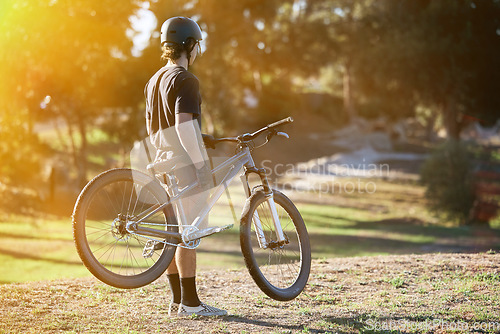 Image of Bike, fitness and summer with a sports man outdoor in nature for leisure or recreation in summer. Back, bicycle and exercise with a male athlete standing on an open green field carrying his transport