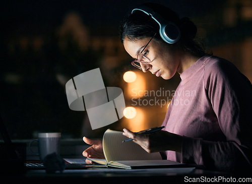 Image of Headphones, research and girl student studying at night for a test, exam or college assignment. University, notes and woman reading while listening to music, radio or podcast in the evening at a desk