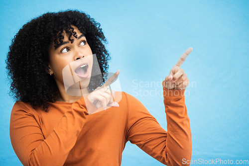 Image of Black woman, surprise and pointing hands in studio for news announcement, gossip notification and blue background. African gen z girl, young female model and fashion for wow, hand sign and happiness