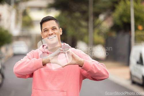 Image of Portrait, hands and heart by man in city, happy and relax, travel and journey on blurred background. Face, traveler and emoji, hands and shape by handsome guy showing icon, love and smile for Mexico