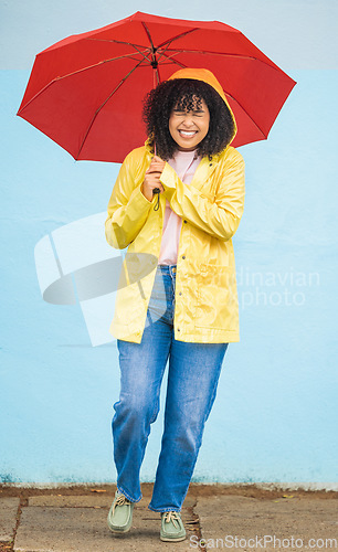 Image of African woman, smile and umbrella by wall with excited face, rain and fashion raincoat in funny moment in city metro. Gen z girl, winter or comic laughing for weather, walk or urban outdoor adventure