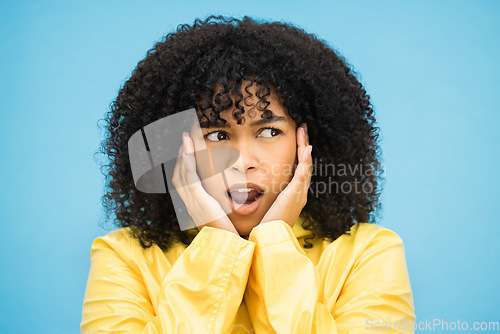 Image of Black woman, afro or shocked face on isolated blue background in raincoat weather change, rainfall or rain. Model, person or surprised student with hands on cheeks in wow, emoji or scared expression