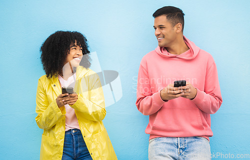 Image of Friends, phone and smile for social media, conversation or communication against a blue studio background. Happy man and woman smiling for networking, 5G connection or chatting on mobile smartphone