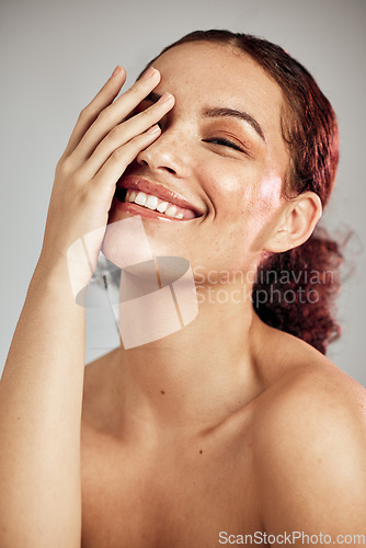 Image of Hand, skincare and portrait of woman in studio for makeup, self care and cosmetics, happy on grey background. Touch, face and girl model smile for beauty, wellness and skin routine while isolated