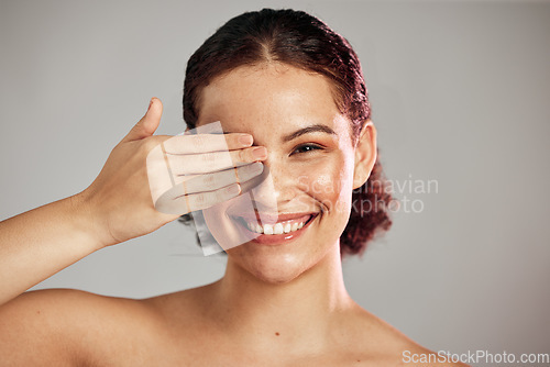 Image of Beauty, hand and portrait of woman in studio for makeup, wellness and grooming against a grey background. Face, covering and shy girl model relax for skincare, hygiene and skin routine while isolated