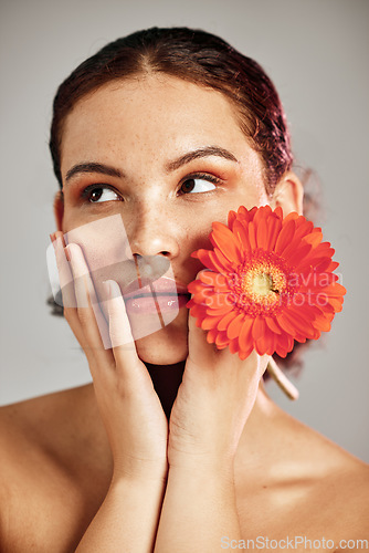 Image of Flower, skincare and glow of a woman with hands on face for dermatology, makeup and cosmetics. Facial, wellness and self care for natural skin, floral product and a healthy model thinking in studio