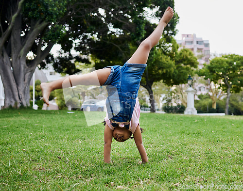 Image of Cartwheel, child and outdoor park fun of a girl in summer with freedom and happiness. Fun, happy and holiday play of a young kid on green grass in nature on a morning with blue sky and smiling