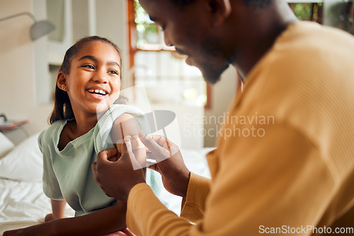 Image of Father, injury and arm bandage for girl after accident in bedroom. First aid, black family and man apply bandaid or plaster on wound of hurt or injured child for wellness, recovery and healthcare.