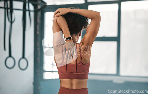 Image of Fitness, back view or black woman in gym stretching to warm up body or relax arm muscles in workout exercise. Wellness, flexible or healthy sports girl training or exercising with focus or motivation