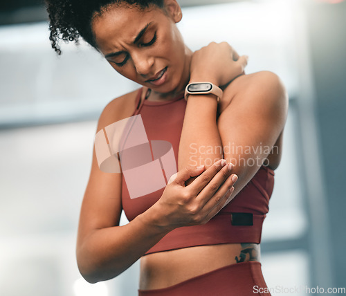 Image of Elbow, pain and fitness with a sports black woman in the gym with a sore joint from an exercise workout. Injury, training and health with a young female athlete struggling with a hurt arm or muscle