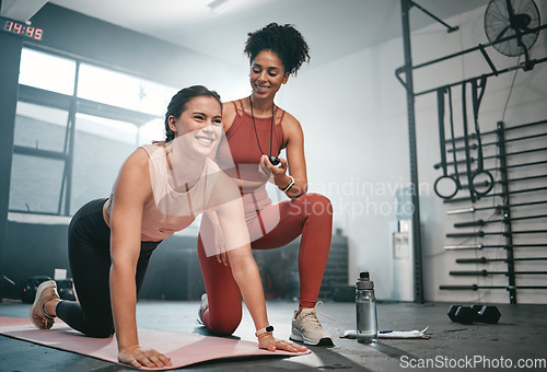 Image of Personal trainer, exercise and stopwatch with a black woman coaching a client in a gym during her workout. Health, fitness or training and a female athlete ready to plank with a coach recording time