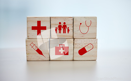 Image of Health, insurance and wooden blocks on empty table in grey studio background for safety or security. healthcare logos, medicine and abstract block toys in a hospital design or clinic for medical care