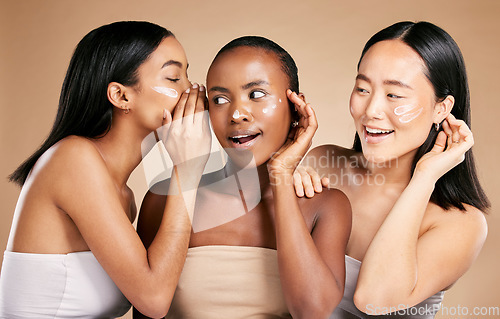 Image of Beauty secret, skincare cream and diversity women friends whisper about inclusion advertising in studio. Asian and black people talk about wow skin glow, spa facial and face with dermatology product