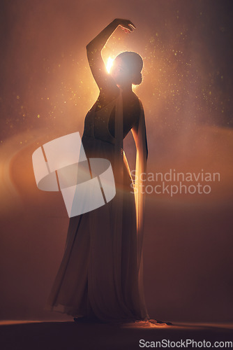 Image of Fantasy, orange lighting and silhouette of woman on stage for creative fashion, art deco and beauty. Ballet dancer, aesthetic and shadow of girl pose for dream, magic and freedom in glowing studio