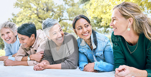 Image of Happy, women and relax at a park, laughing and bonding while lying on a blanket together. Diversity, friends and woman group bonding, funny and enjoying comic, humor and goofy joke while on a picnic