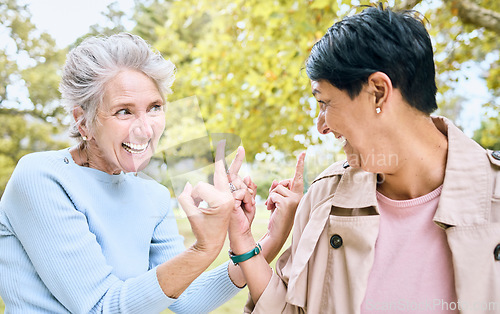 Image of Elderly, women and middle finger at the park for fun, humor and silly while laughing together. Mature, friends and females with hand, emoji and gesture, playful and happy, smile and bonding in nature