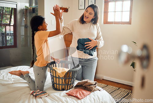 Image of Cleaning, high five and child and mother doing laundry clothes, house work and fold clean fabric. Love bond, home bedroom or happy family kid with basket container and celebrate domestic housekeeping