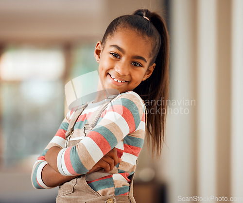 Image of Happy, smile and portrait of a girl child in her home with a positive mindset standing with crossed arms. Happiness. beautiful and young kid with a casual, stylish and trendy outfit posing in house.