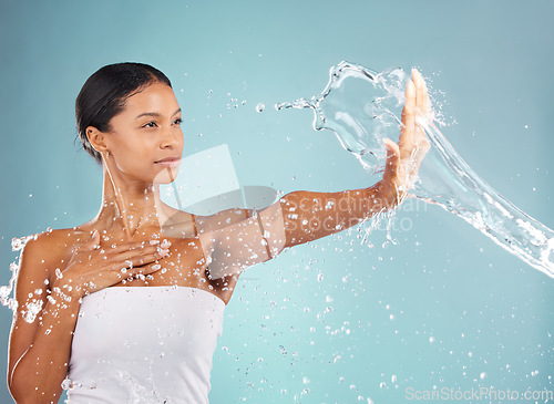 Image of Water splash, hand and woman with skincare, beauty and wellness ready for a shower. Blue background, studio and isolated female model with dermatology, skin glow and cleaning treatment feeling calm