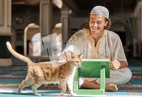 Image of Muslim, man and cat in a mosque, happy and smile during, worship, prayer and bonding. Islamic, male and animal in holy, religious place for praying, humble and sitting for pray and learning