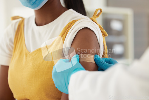 Image of Vaccine, covid and a plaster on the arm of a black woman in a hospital for healthcare. Nurse, doctor and medical with a medicine professional in a clinic to apply a bandaid after corona vaccination