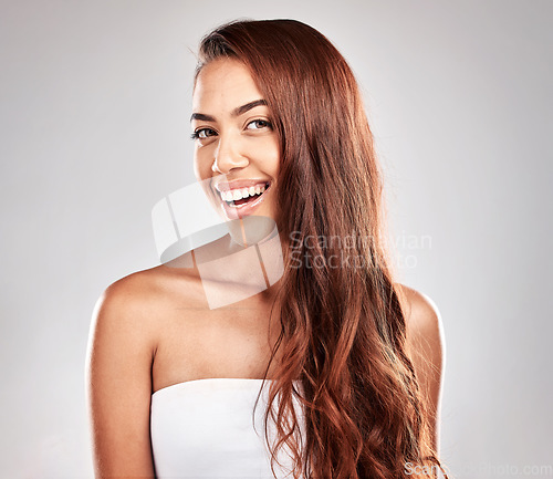 Image of Hair care, beauty and portrait of a woman in studio for a keratin, brazilian or botox hair treatment. Happy, smile and female model with a wavy, long and shiny hair style isolated by gray background.