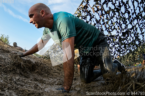 Image of Athletes crawling through mud