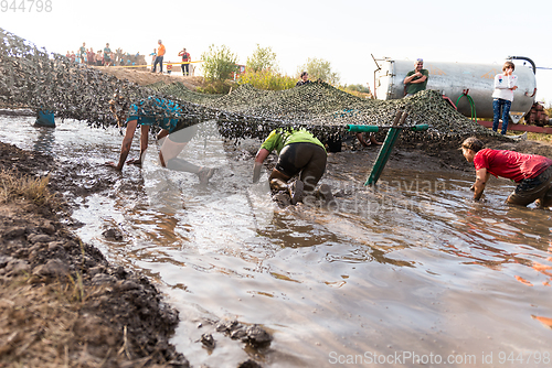 Image of Athletes crawling through mud