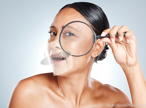 Image of Magnifying glass, skincare and mature woman in a studio with a health, wellness and natural face routine. Beauty, cosmetic and portrait of a female with a lens for an anti aging facial treatment.