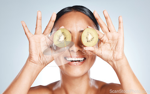 Image of Skincare, beauty and woman with kiwi on eyes for vitamin c facial detox and smile on studio background. Healthy skin care, wellness and sustainability, organic luxurycleaning and grooming with frui