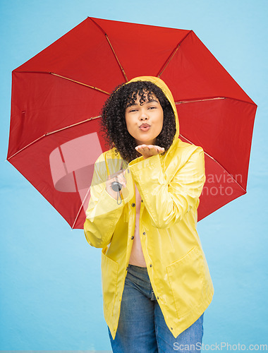 Image of Portrait, black woman and umbrella in a city for kiss, travel and flirting on a solo trip against wall background. Face, blowing kiss and girl traveler relax in rainfall, excited and emoji gesture