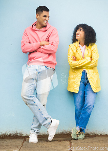 Image of Happy couple, smile and cool fashion standing in urban town wall background for conversation, peace and relax together. Casual man, trendy woman and happiness speaking for millennial street style